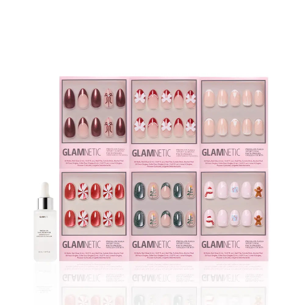 Six boxes of glamnetic All Decked Out winter press-on nails with festive holiday designs are arranged in two rows, with a white bottle of glamnetic cuticle oil to the left, all displayed on a white background. - Product image
