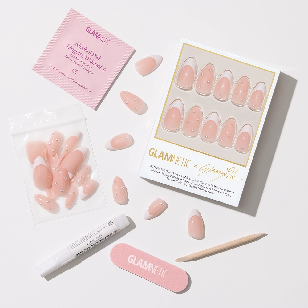 Flat-lay of the full nail kit contents: the boxed nail set, loose nails in a ziplock pouch, a Glamnetic nail glue pen, a pink nail file, a wooden cuticle stick, and an alcohol pad—all arranged neatly against a white background.
- Product image