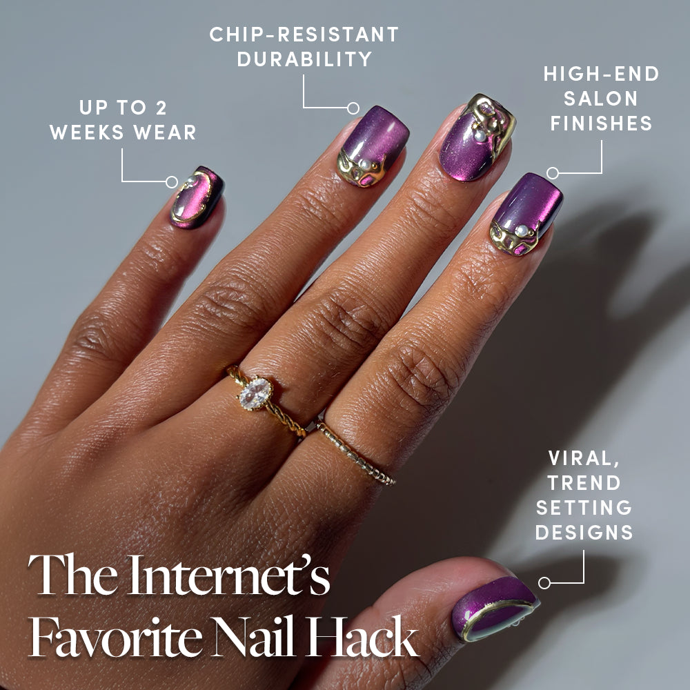 A hand adorned with the glamnetic Amethyst Press-On Nails in a chic short squoval shape, featuring a luxurious velvet purple finish alongside gold rings and decorative accents. The photo highlights their long-lasting wear, chip resistance, high-end finishes, and on-trend design—making this set an essential nail hack to try. - Product image