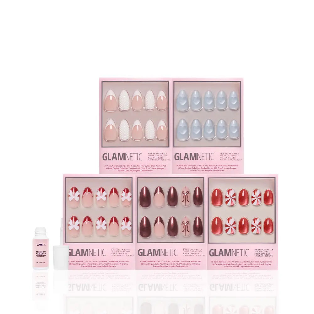 Six boxes of glamnetic Ann's Festive Five almond press-on nails in pink, red, blue, white, and peppermint patterns are displayed in two rows, with a glue bottle in front—ideal for party-ready manicures or a festive holiday nail look. - Product image
