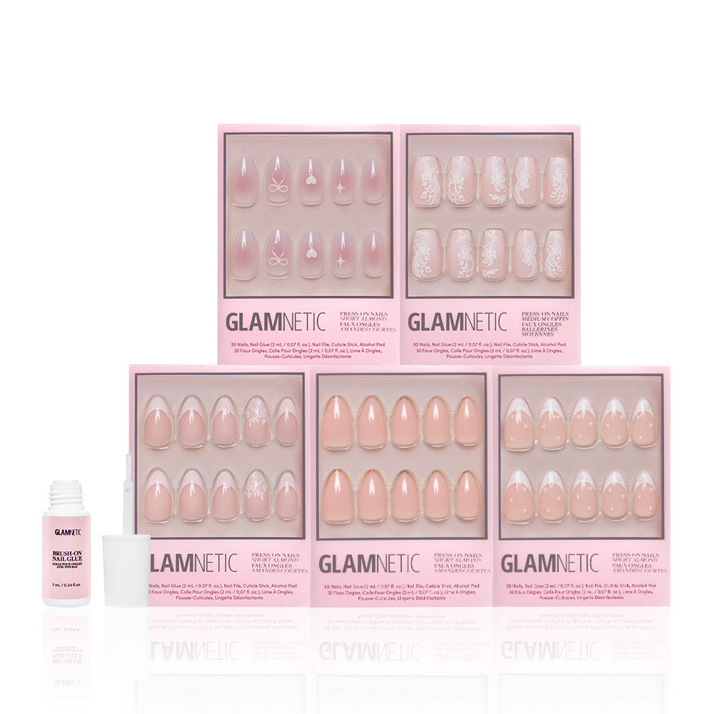 Six boxes of glamnetic Anns Sweethearts press-on nails in light pink and white, with floral, geometric, and French tip designs in a short almond style, are arranged in two rows. A small bottle of glamnetic nail glue is on the left. - Product image