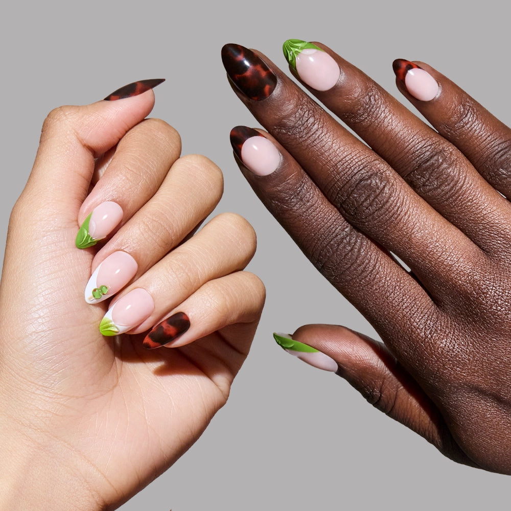 Two hands of different skin tones display glamnetic Antipasto almond-shaped press-on nails, featuring tortoiseshell designs on some fingers and green leafy tips on others, set against a plain gray background. - Product image