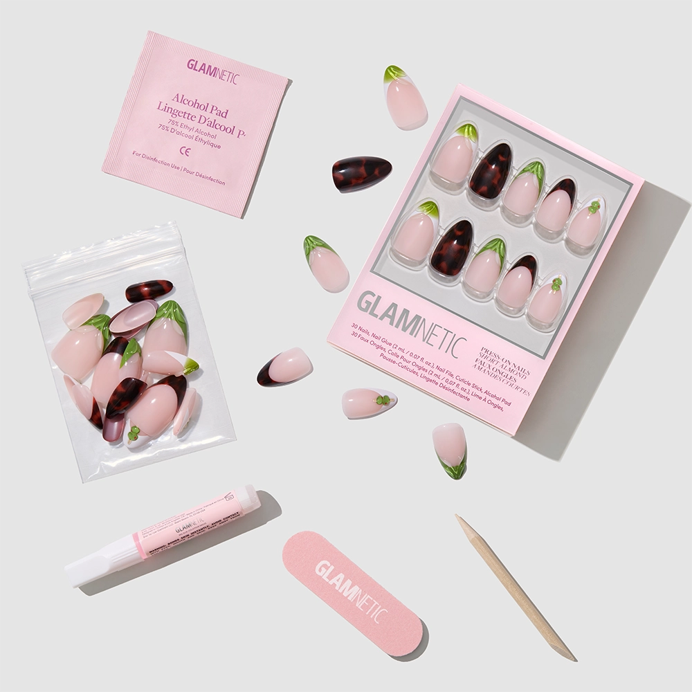 The Glamnetic Antipasto set features almond press-on nails in pink, green, and tortoiseshell, displayed with a nail file, wooden cuticle stick, glue tube, alcohol pad, and extra nails on a light background. - Product image