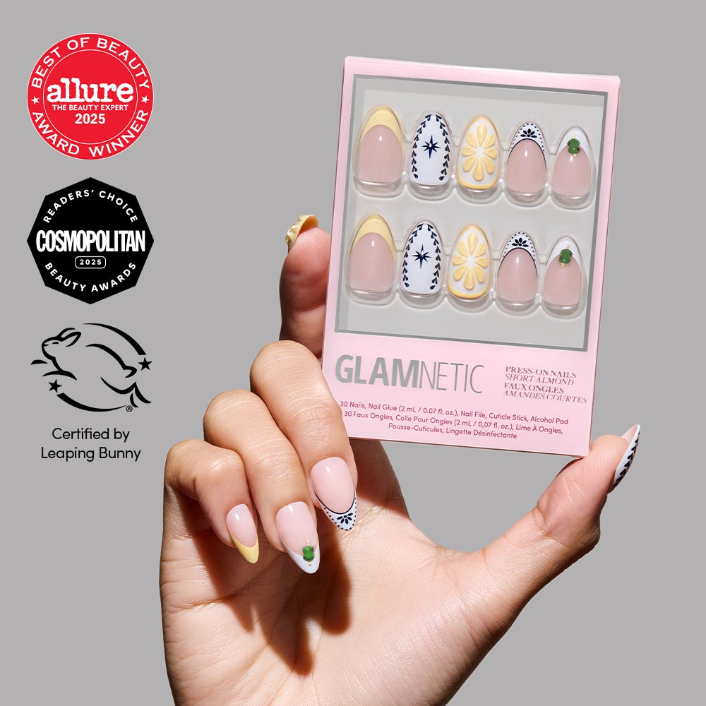 A hand with stylish short almond nails holds a box of glamnetic’s Aperitivo Hour press-ons featuring floral and geometric designs, shown alongside Allure, Cosmopolitan beauty awards, and Leaping Bunny certification badges.
