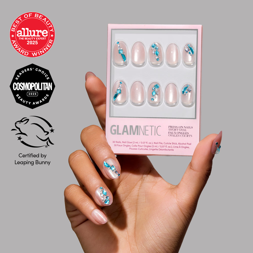 A hand with decorated nails holds a box of glamnetic Aquamarine press-on nails, featuring a blue and white floral design. Allure, Cosmopolitan, and Leaping Bunny award logos are displayed on the left against a gray background.