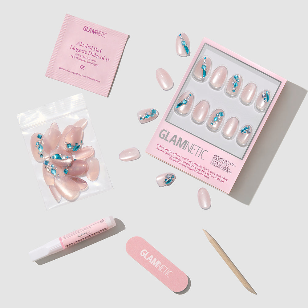 The glamnetic Aquamarine press-on nail set features blue and silver designs and includes an alcohol pad, nail glue, pink nail file, wooden cuticle stick, and extra nails, all displayed on a white surface. - Product image