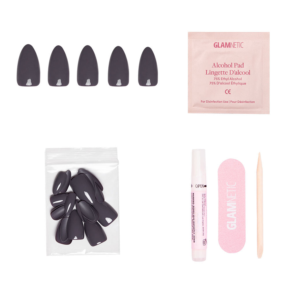 Ash Gray almond press-on nails from glamnetic’s Fall Forest Collection, featuring black nails, alcohol pad, extra nails bag, nail glue pen, pink file, and cuticle stick displayed on a white background. - Product image