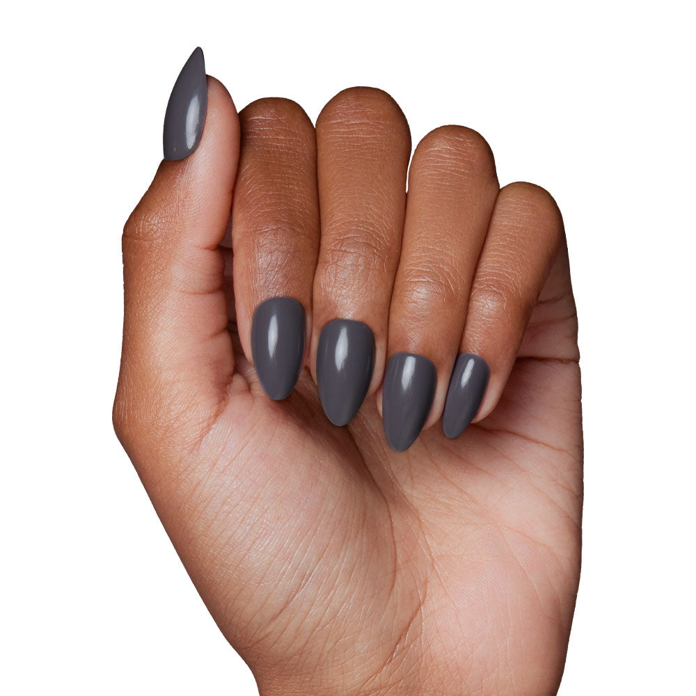 A hand with medium brown skin and slightly curled fingers shows long, almond nails painted in glamnetics Ash Gray from the Fall Forest Collection, set against a plain white background. - Product image