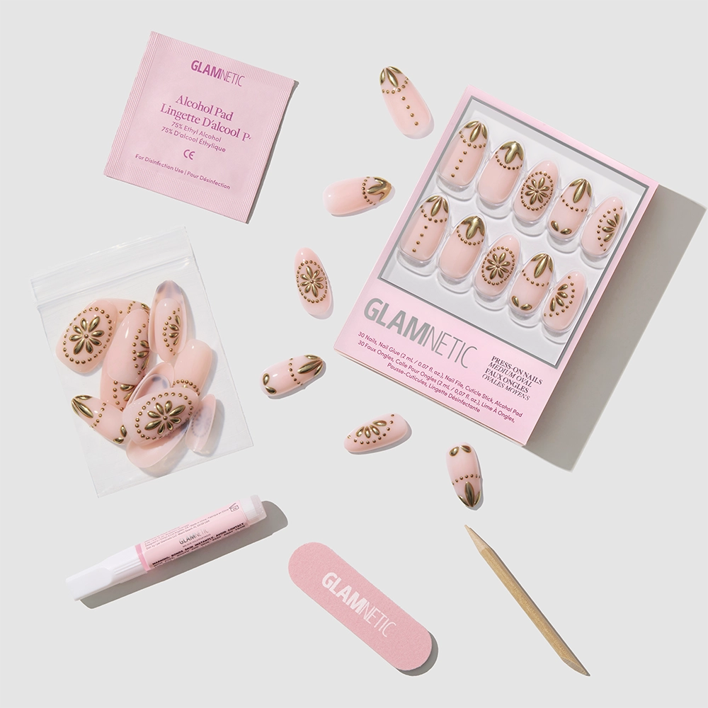 The glamnetic Athenian Gold Press-On Nails set features gold-patterned nails, a pink nail file, cuticle stick, nail glue, alcohol pad, and extra cruelty-free nails arranged neatly on a light background. - Product image