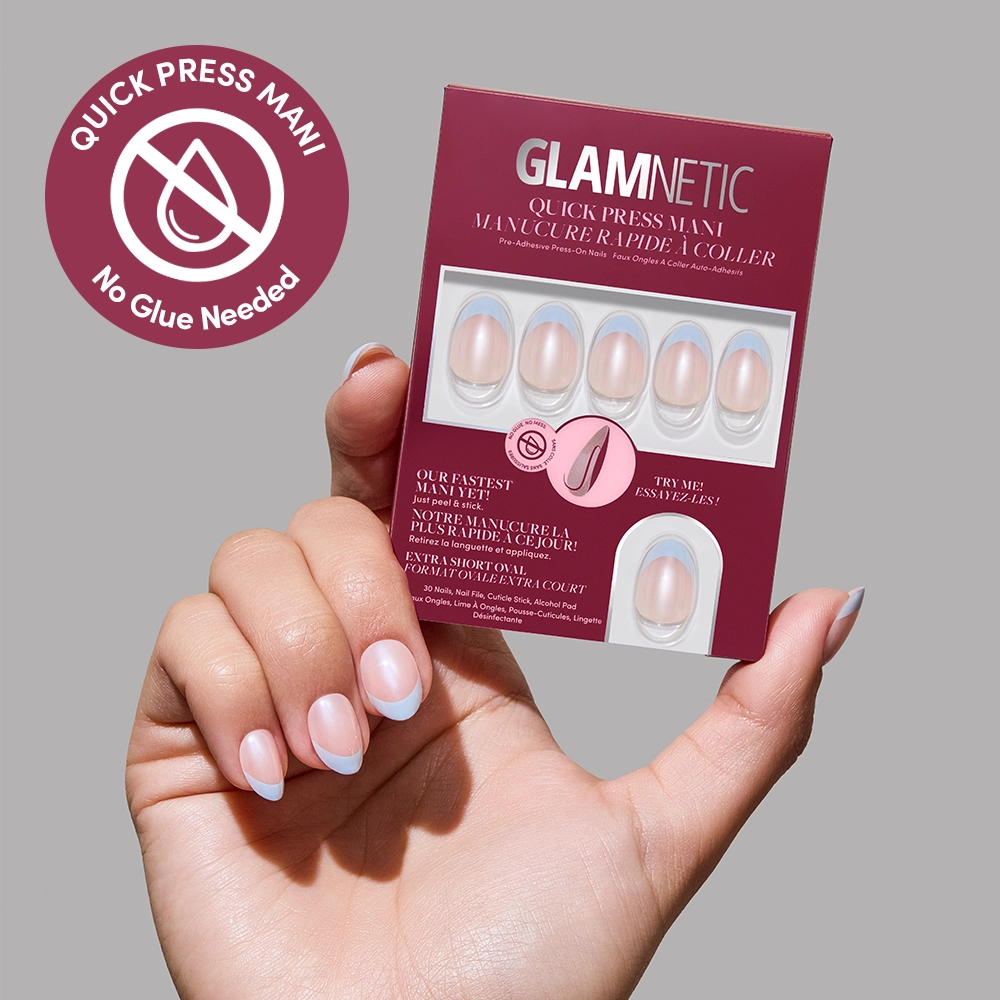 A hand with light blue and white French-tip no-glue nails holds a glamnetic Blue Halo Quick Press Mani box, showing six press-on nails, indicating no glue needed, and featuring the Quick Press Mani logo in the top left.