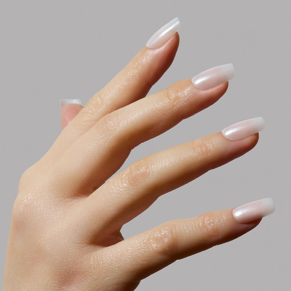 A hand with long, neatly manicured medium square nails painted in a glossy light pink Bailey shade by glamnetic is shown against a plain gray background. - Product image