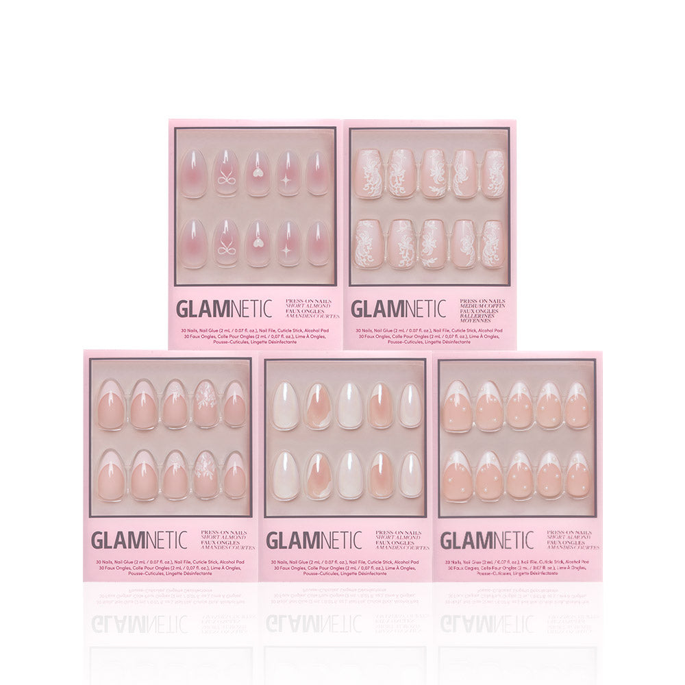 Five boxes of Glamnetic Be Mine press-on nails are displayed against a white background, featuring various pink and nude designs like flowers, French tips, hearts, and solid styles. Each box showcases a unique pattern. - Product image