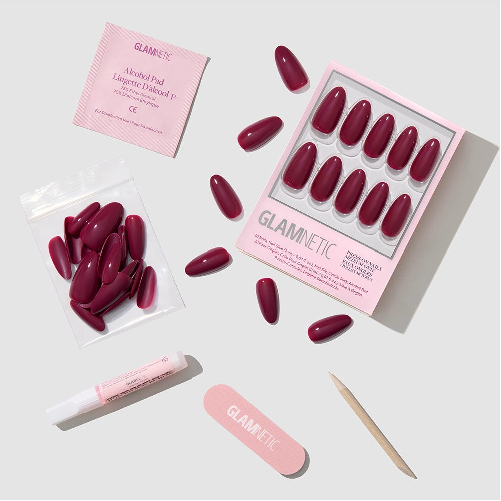 Berry Tempted by glamnetic: a burgundy press-on nail set with glue, alcohol pad, nail file, cuticle stick, and extra nails—all neatly arranged on a white background.