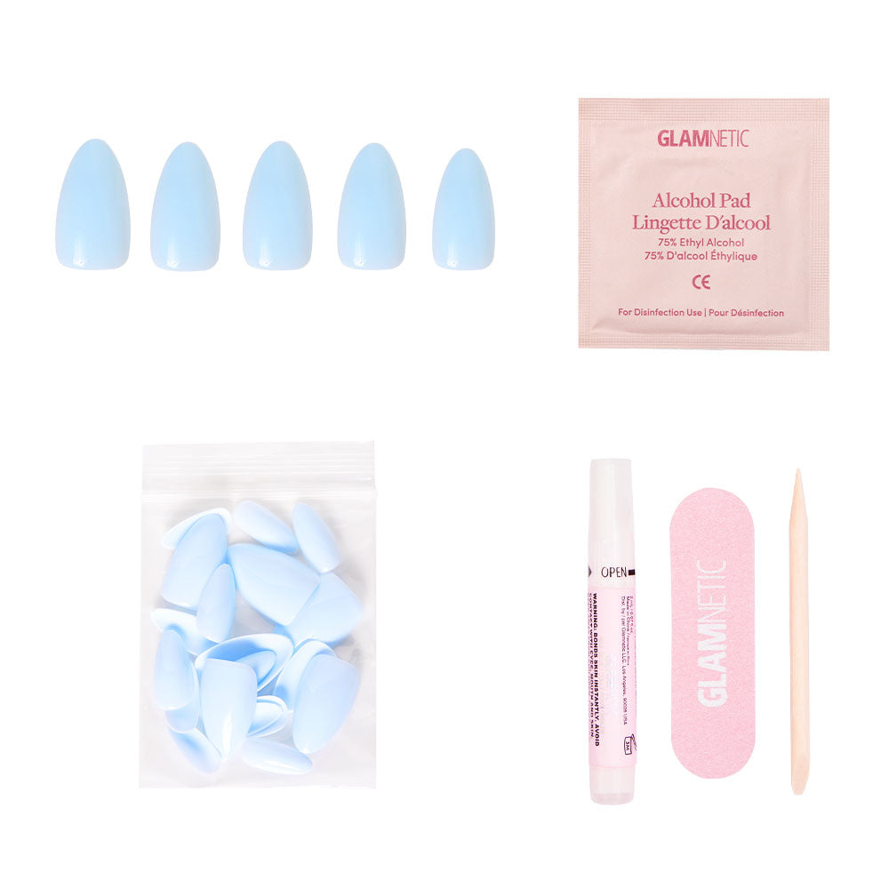 The glamnetic Blueberry Milk set includes glossy blue press-on nails, a nail glue pen, extra nails, an alcohol pad, pink nail file, and wooden cuticle stick—arranged on a white background. - Product image