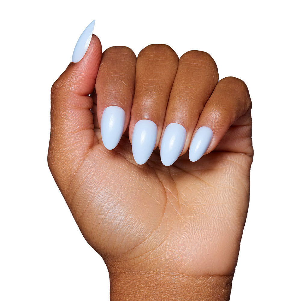 A hand with medium brown skin shows long, almond-shaped nails in a glossy light blue shade, featuring the Blueberry Milk set by glamnetic, against a white background. - Product image