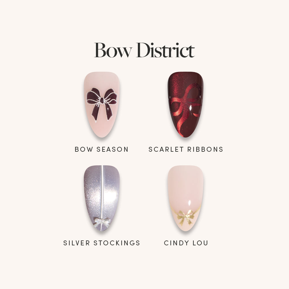 Showcasing elegant 3D press-on nails from glamnetic’s Bow District collection, this set features four chic designs: pale pink with a dark bow accent, deep red with a matching red bow, metallic silver with a sleek center stripe, and pale pink topped with a gold bow at the tip. The text highlights “Bow District” alongside the individual shade names—perfect for anyone seeking stylish and sophisticated press-ons. - Product image