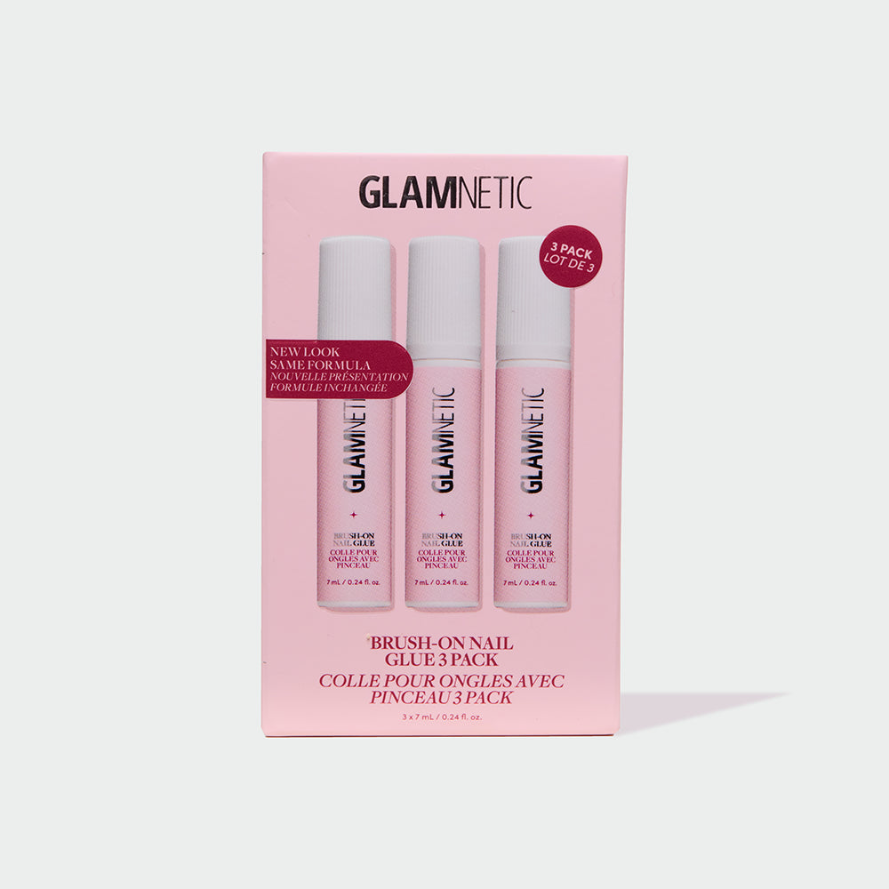 A pink box labeled glamnetic Glue Trio contains three tubes of Brush-On Nail Glue, perfect for securing your favorite press-on nails. The packaging showcases "3 pack" and "new look, same formula," making it easy to achieve a salon-quality manicure at home. Text appears in both English and French, with images of the glue tubes visible through the front.