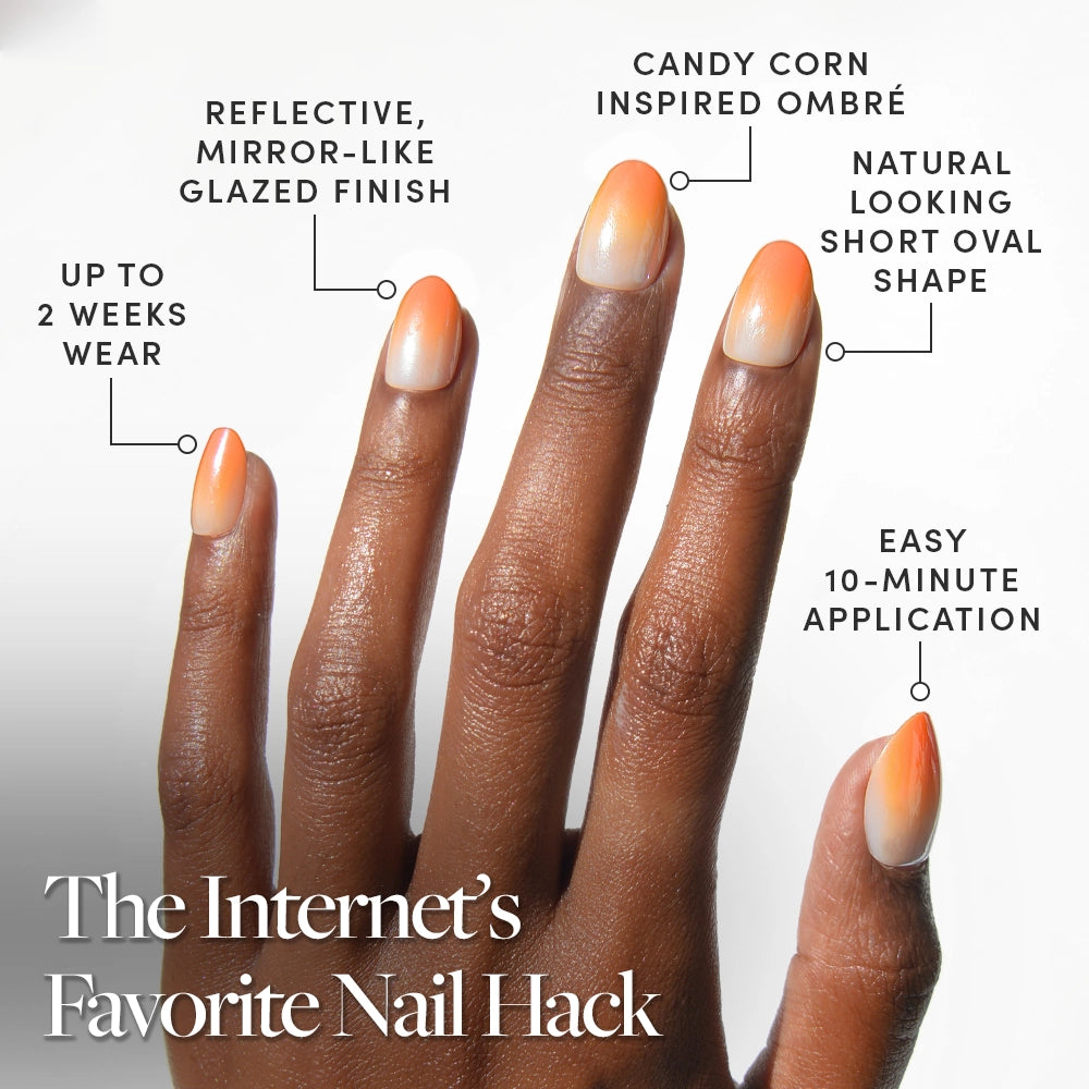 A hand with long almond-shaped nails in an orange and nude gradient design. Candy Corn by glamnetic offers up to 2 weeks wear, chip-resistant durability, and viral Halloween styles for a high-end salon finish. - Product image