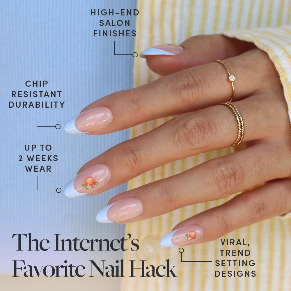A hand with Capri Coast medium oval nails by glamnetic, featuring French tips and peach decals. Text highlights chip resistance, salon-quality finish, up to 2 weeks wear, trending press-ons. Hand wears gold rings and a striped shirt. - Product image