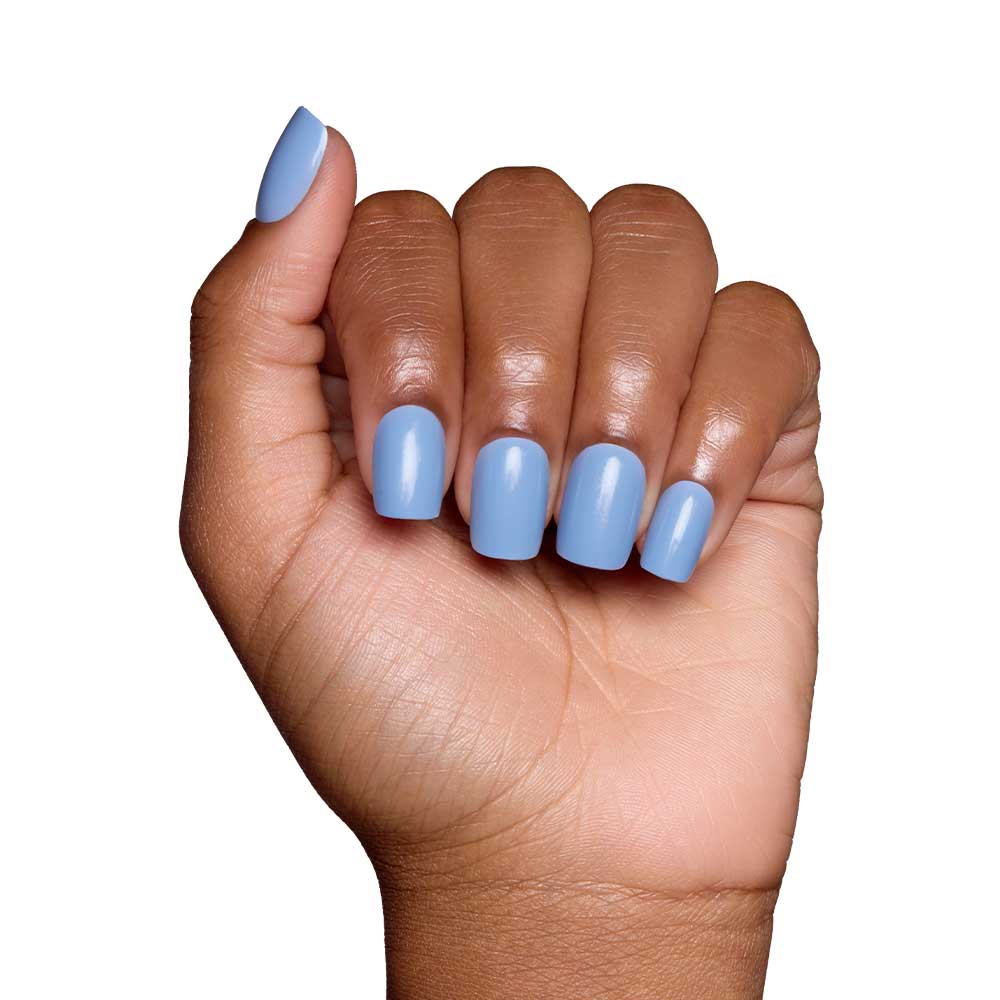 A hand with medium brown skin displays short squoval nails painted in glamnetic’s Cashmere Blue, a glossy light blue shade. The fingers are gently curled inward against a plain white background. - Product image