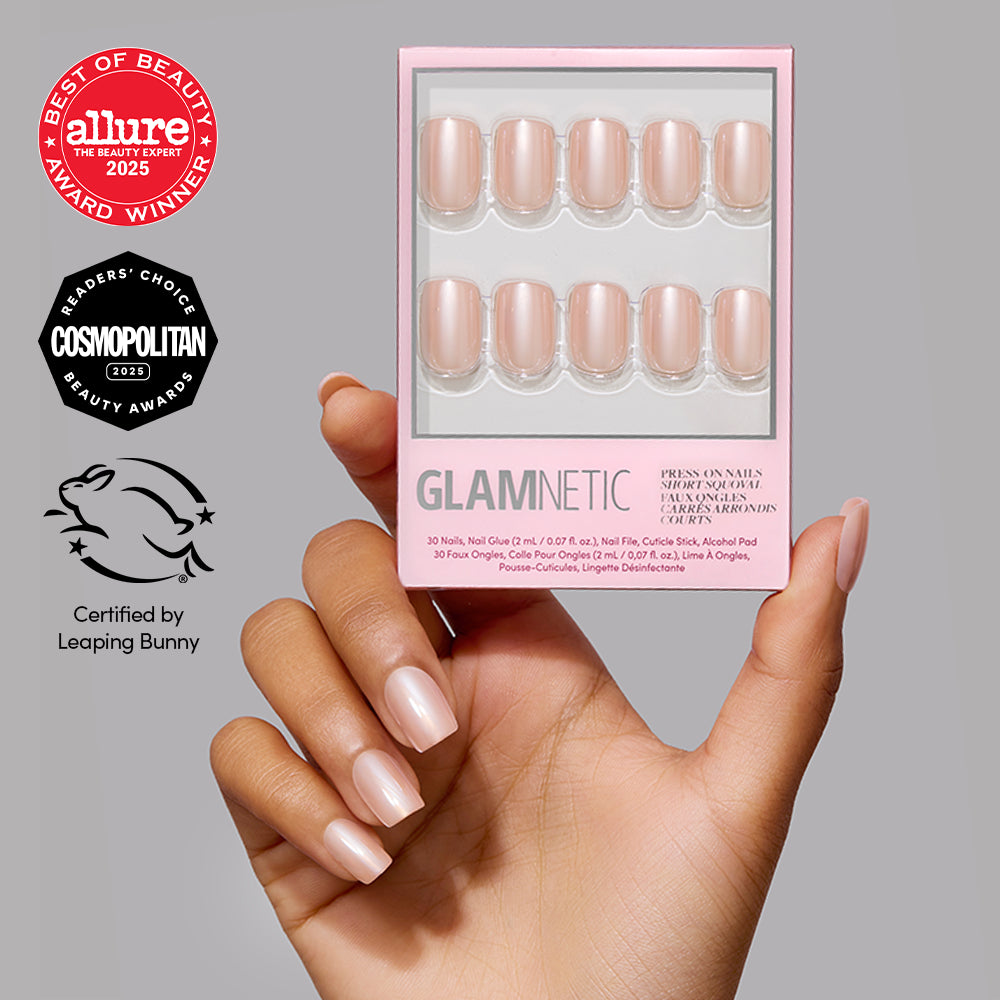 A hand with short, squoval, light-pink press-on nails holds a box of Champagne Veil nails, displayed next to Allure and Cosmopolitan award icons and a Leaping Bunny certification logo. - Product image