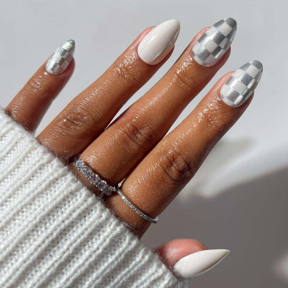 Glamnetic Check-Mated short almond-shaped press-on nails featuring a mix of solid off-white polish and a metallic silver checkered pattern. - Product image