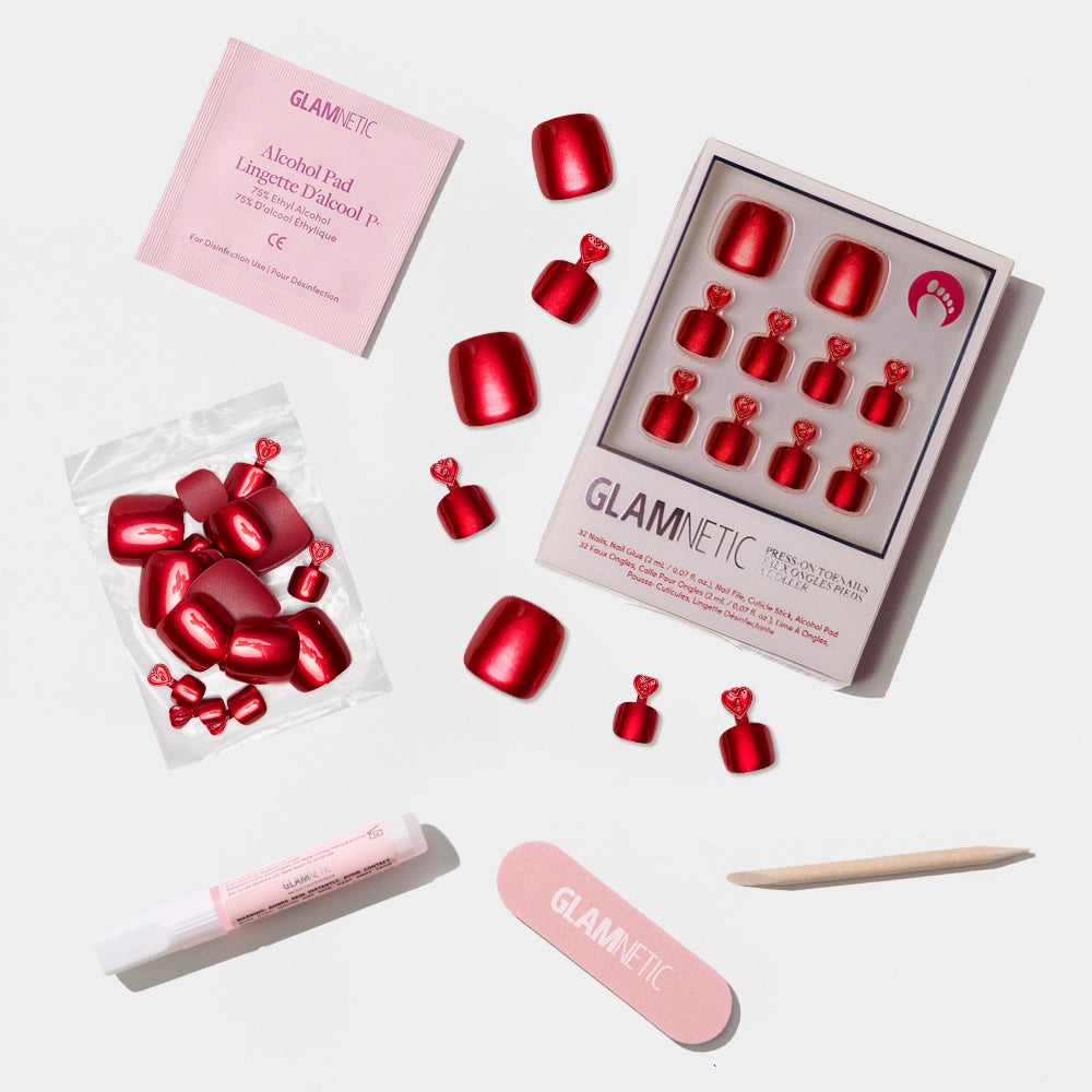 A flat-lay of the Glamnetic metallic ruby red press-on toenail kit with all nail prep and application tools. - Product image
