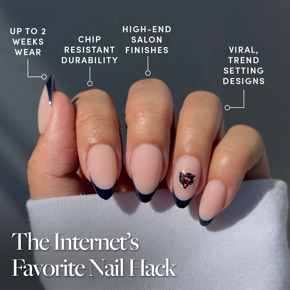 A chic hand with nude and black French tip nails, featuring a gem accent, shows off the glamnetic Chicago Bears Press-On Nail Set—offering up to 2 weeks’ wear, chip resistance, luxe finishes, and trend-forward style. - Product image