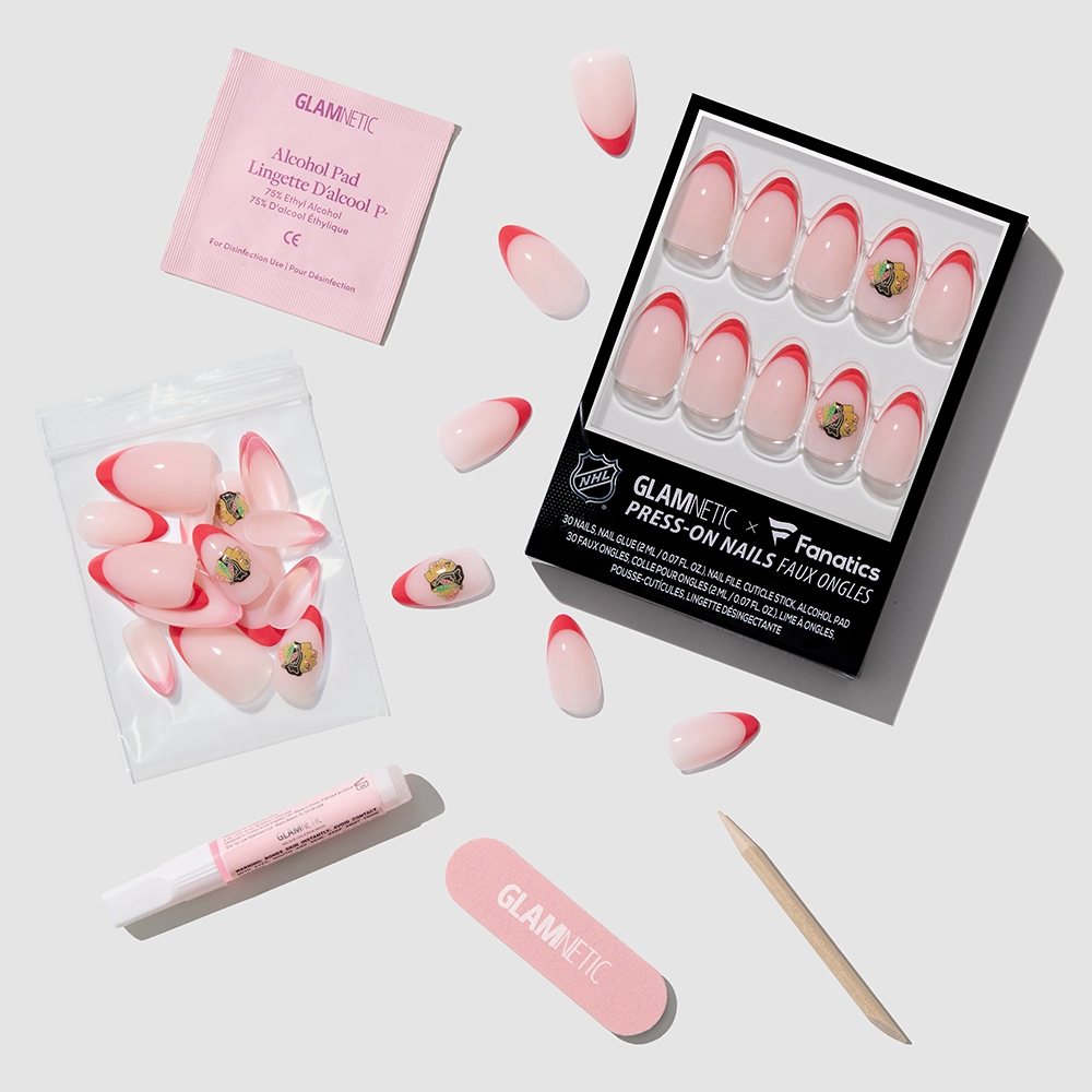 The glamnetic Chicago Blackhawks Press-On Nail Set features pink and red fandom French tips with a small logo, plus a nail file, cuticle stick, glue, alcohol pad, and extra nails arranged on a light gray background. - Product image