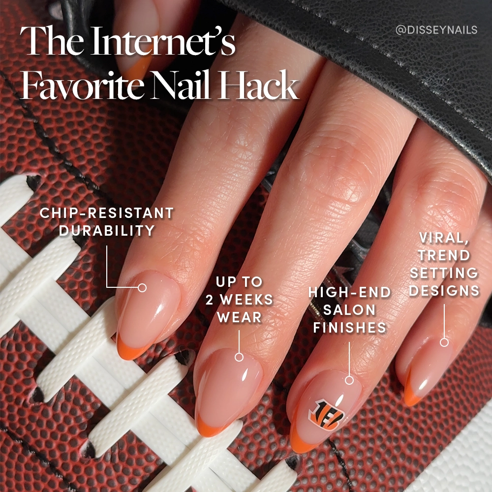 A hand with a French manicure featuring orange tips and a Cincinnati Bengals logo holds a football, highlighting glamnetics Cincinnati Bengals Press-On Nail Set—chip-resistant, salon-quality, lasting up to two weeks in bold, trendsetting designs. - Product image