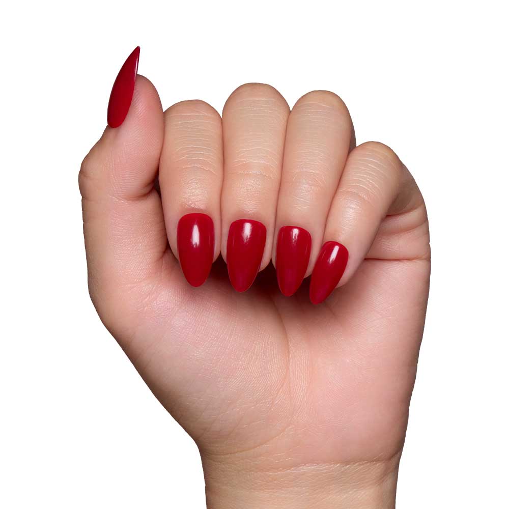 A hand with long, almond-shaped nails wears the glossy Classic Red set by glamnetic, displayed against a plain white background. - Product image