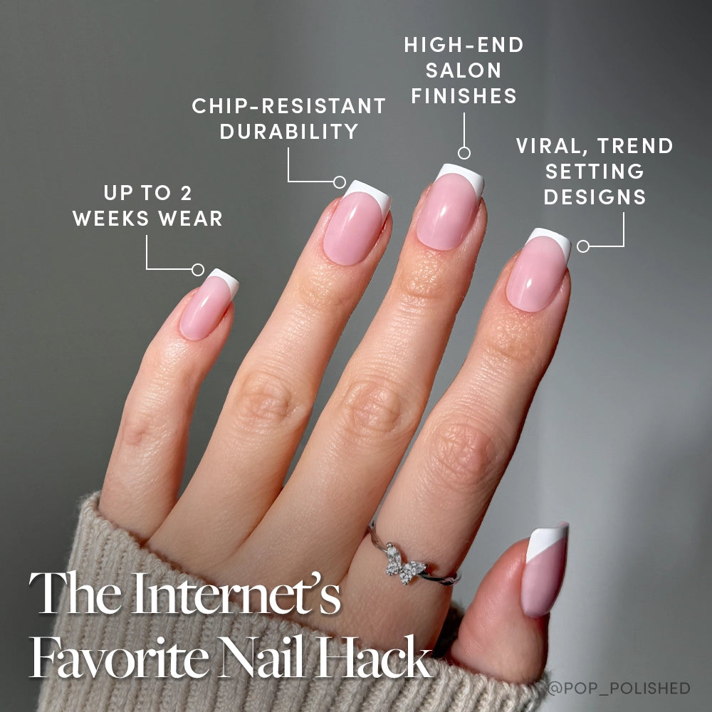 A hand with neatly manicured, pale pink Classy French nails by glamnetic features French tips and a modern twist. Benefits include up to 2 weeks wear, chip-resistant durability, salon-quality finish, and trend-setting style. A silver ring is worn. - Product image
