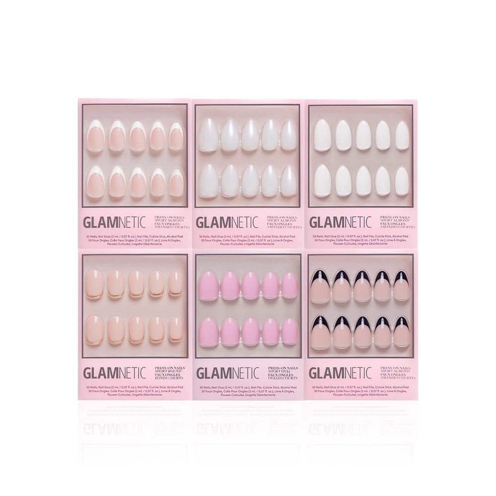 Six glamnetic Clean Girl Aesthetic press-on nail sets in pink boxes, each with almond-shaped nails featuring unique nude, white, pink, and black designs, are displayed against a white background. - Product image