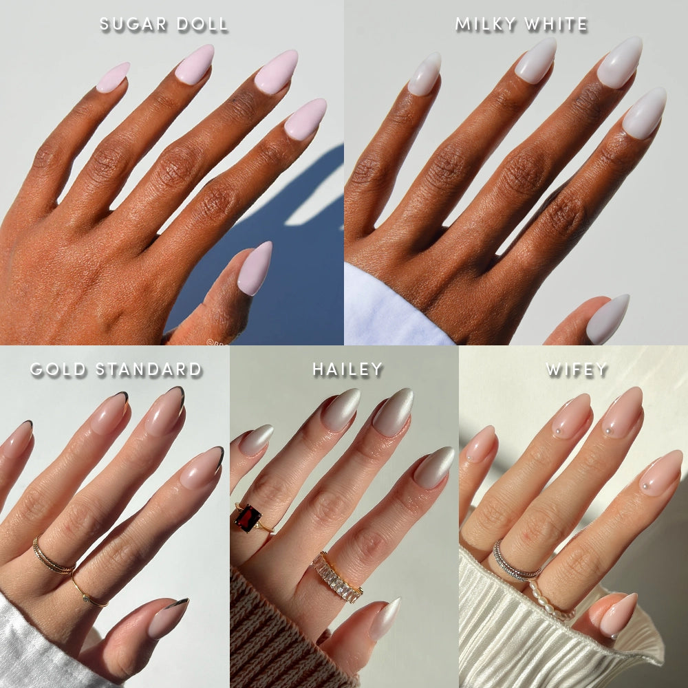 Five manicured hands display different nail colors—Sugar Doll (soft pink), Milky White (milky white), Gold Standard (nude), Hailey (white with gold tips), and Wifey (pinkish nude)—each labeled above the hand. Featuring short almond shapes, glamnetic’s Clean Girl Almonds press-on nails deliver a salon-quality manicure, showcasing chic, milky nails in on-trend shades perfect for any occasion. - Product image