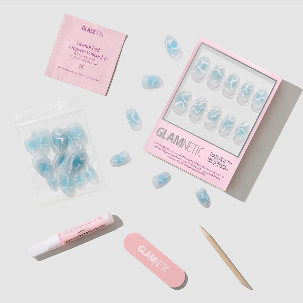 Glamnetic Cloud Dance press-on nail kit featuring short oval nails in a stunning blue velvet finish, including an alcohol pad, tube of glue, mini nail file, cuticle stick, and extra press-on nails—all beautifully displayed on a light background. - Product image