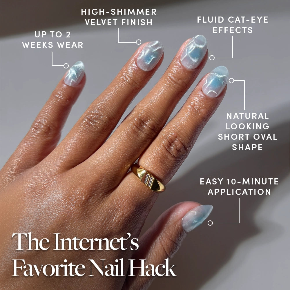 A hand with glossy, light blue Cloud Dance cat-eye press-on nails by glamnetic is shown, featuring a high-shimmer velvet finish, short oval shape, easy 10-minute application, and lasting up to 2 weeks. A gold ring adorns the middle finger. Text reads: The Internet’s Favorite Nail Hack. - Product image