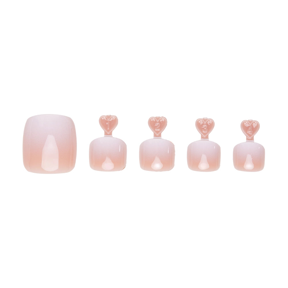 Peachy nude ombre press-on toenails in five sizes, each with heart-shaped tabs for application. - Product image