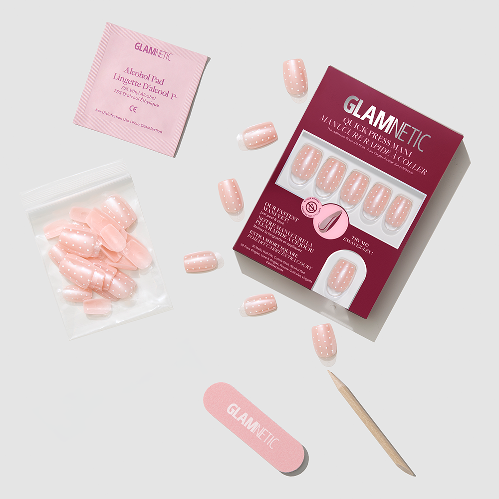 The glamnetic Dainty Dots press-on nail kit includes pink polka dot nails, a pink nail file, wooden cuticle stick, nail glue, alcohol pad, and extra nails—all you need for a quick press mani. - Product image