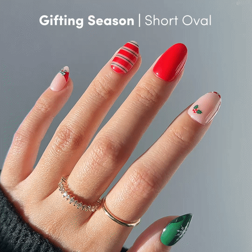 Gifting Season - A hand with short oval nails, each painted in festive Christmas designs—red stripes, holly, and green snowflakes—from glamnetic’s Gifting Season set. Gold rings on two fingers. Text above reads: Gifting Season | Holiday Nail Set.