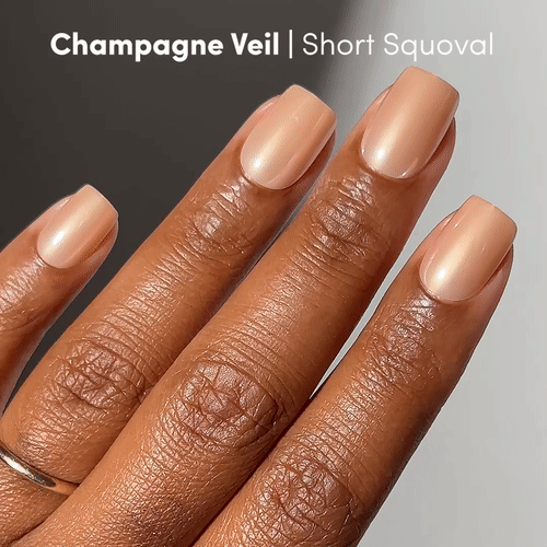 A medium brown hand with short squoval nails painted in glamnetic Champagne Veil, a sheer champagne shade, giving a chic look similar to Champagne press-on nails.