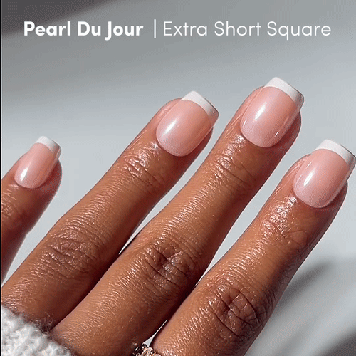 A hand with neatly manicured extra short square press-ons, Pearl Du Jour by glamnetic, featuring classic French tips—white edges and a soft pink base. Text reads: Pearl Du Jour | Extra Short Square. - Product image