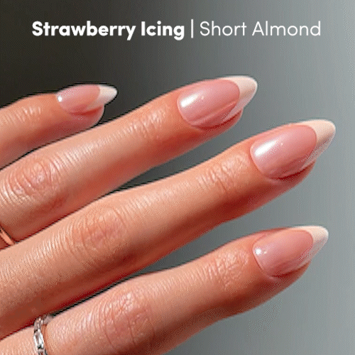 A hand with short almond-shaped nails showcases a glossy, light pink manicure from the glamnetic Strawberry Icing Press-On Nail Set. Text reads: Strawberry Icing | Short Almond on a gradient gray background. - Product image