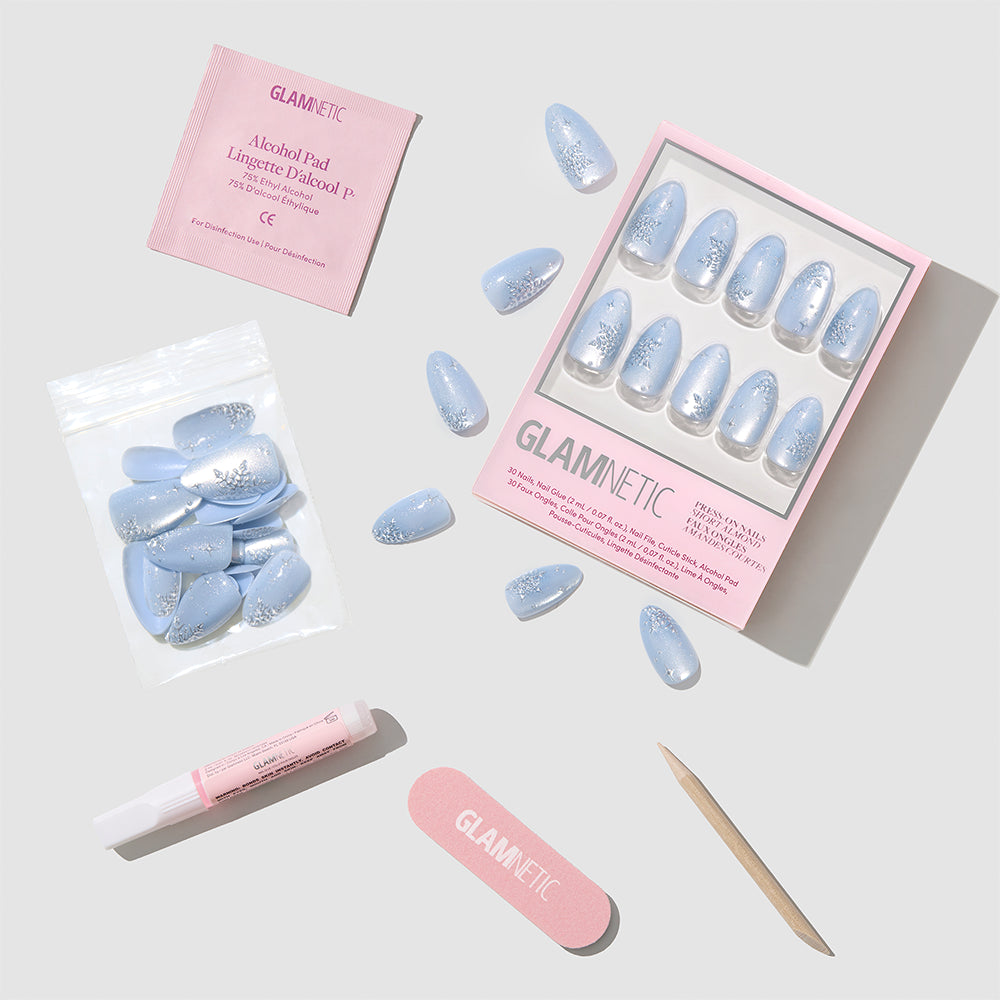 Glamnetic December Sky short almond press-on nails featuring a blue and silver velvet glitter gradient, packaged with nail glue, a file, a cuticle stick, and an alcohol prep pad. - Product image