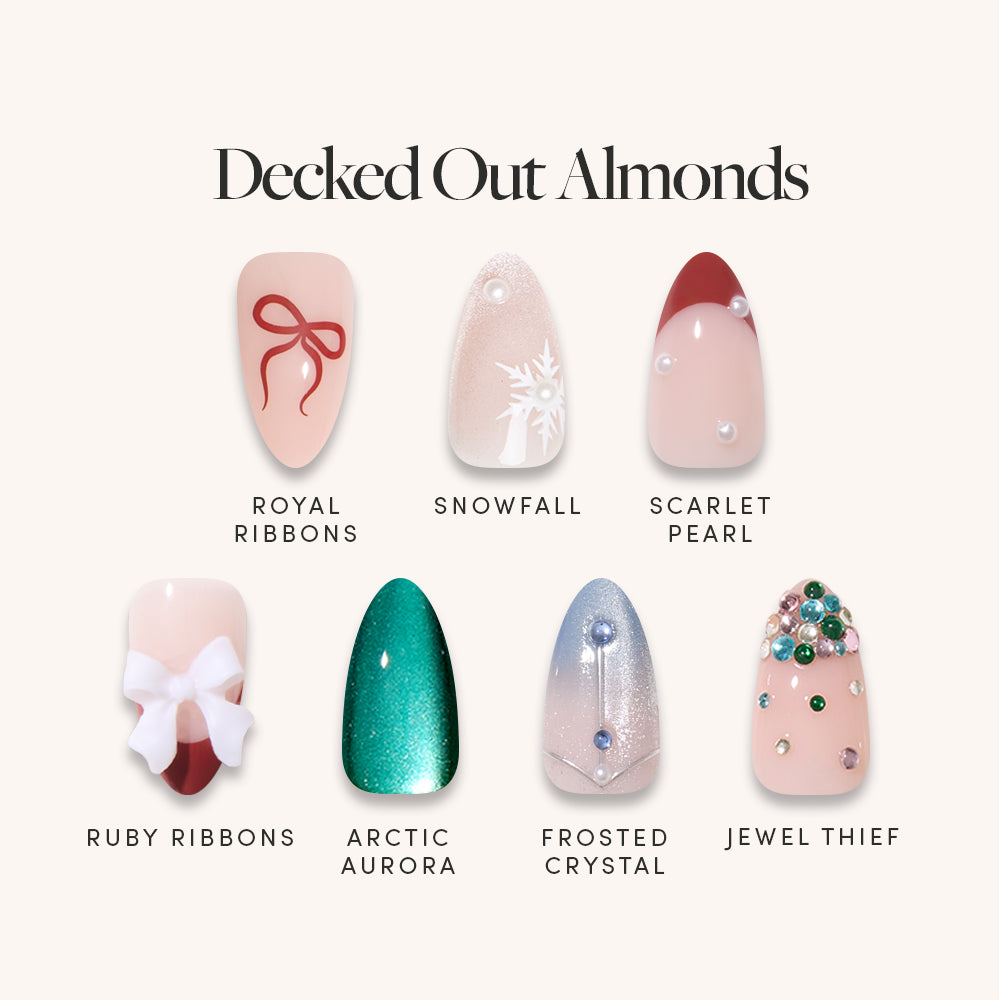 Seven short almond Decked Out Almonds press-on nails featuring holiday-themed designs: Royal Ribbons, Snowfall, Scarlet Pearl, Ruby Ribbons, Arctic Aurora, Frosted Crystal, and Jewel Thief.