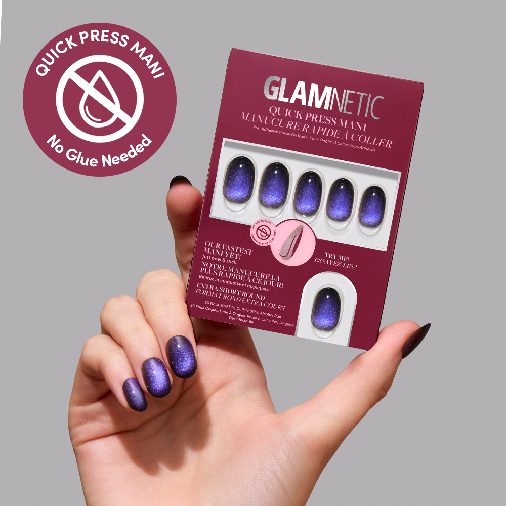 A hand displays velvet effect purple press-on nails called Deep Winter next to a glamnetic press-on nails package. A circular label reads Quick Press Mani, No Glue Needed. The packaging reveals similar extra short press-on nails inside and highlights that these cruelty-free nails from glamnetic offer easy, stylish wear. - Product image