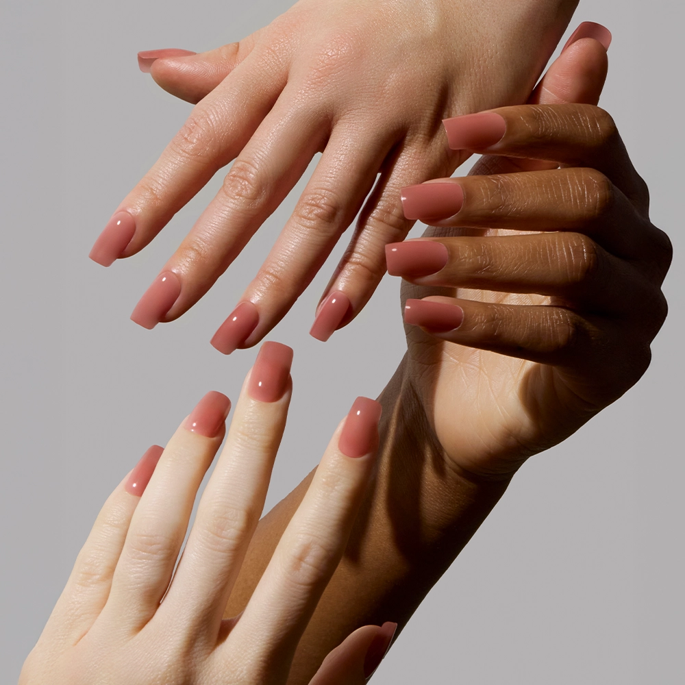 Three hands of different skin tones show off neatly manicured, medium square nails in the matte Dusty Pink shade by glamnetic, against a plain light gray background. - Product image
