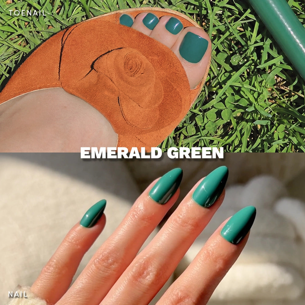 A close-up of toes in tan sandals on grass and fingers with almond-shaped nails, all painted with glamnetic’s Emerald Green Mani & Pedi. The text reads EMERALD GREEN. - Product image