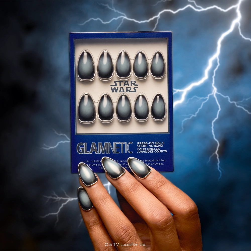 A hand with metallic gray and black almond press-on nails holds the glamnetic Emperor press-on nail set against a stormy background illuminated by lightning, showcasing stylish and cruelty-free nails for every fan. - Product image