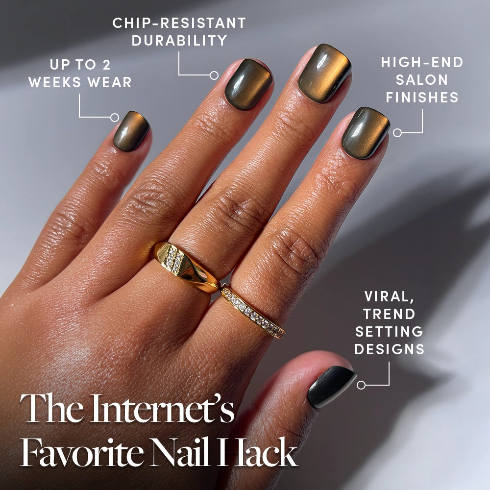 A hand showcases the glamnetic Enstatite Press-On Nails in a metallic olive-green shade, styled in a short length and complemented by two gold rings. The text highlights their chip-resistant durability, salon-quality wear lasting up to 2 weeks, high-end professional finishes, and viral, trendsetting designs. - Product image