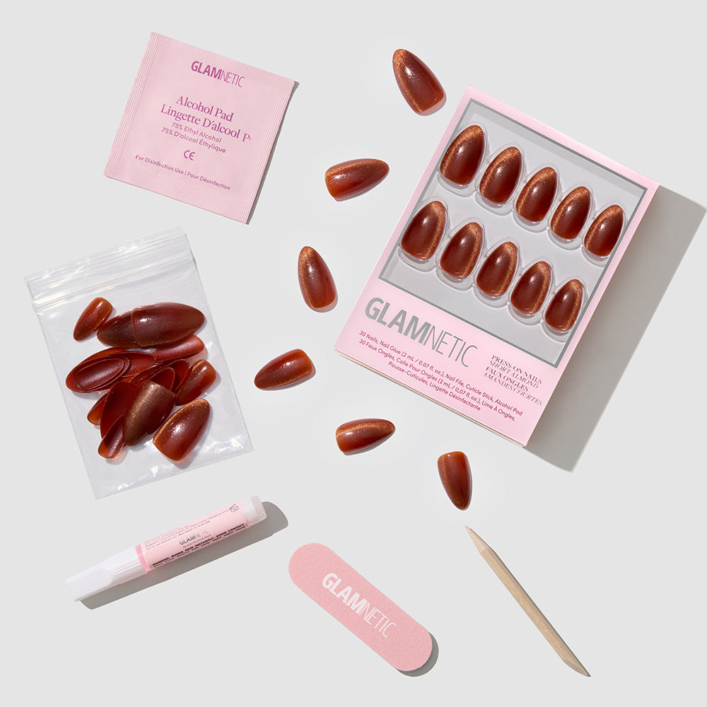 The glamnetic Sicilian Sun set features short almond velvet-finish press-on nails, a pink nail file, wooden cuticle stick, nail glue tube, alcohol pad, and extra cruelty-free nails neatly arranged on a white background. - Product image